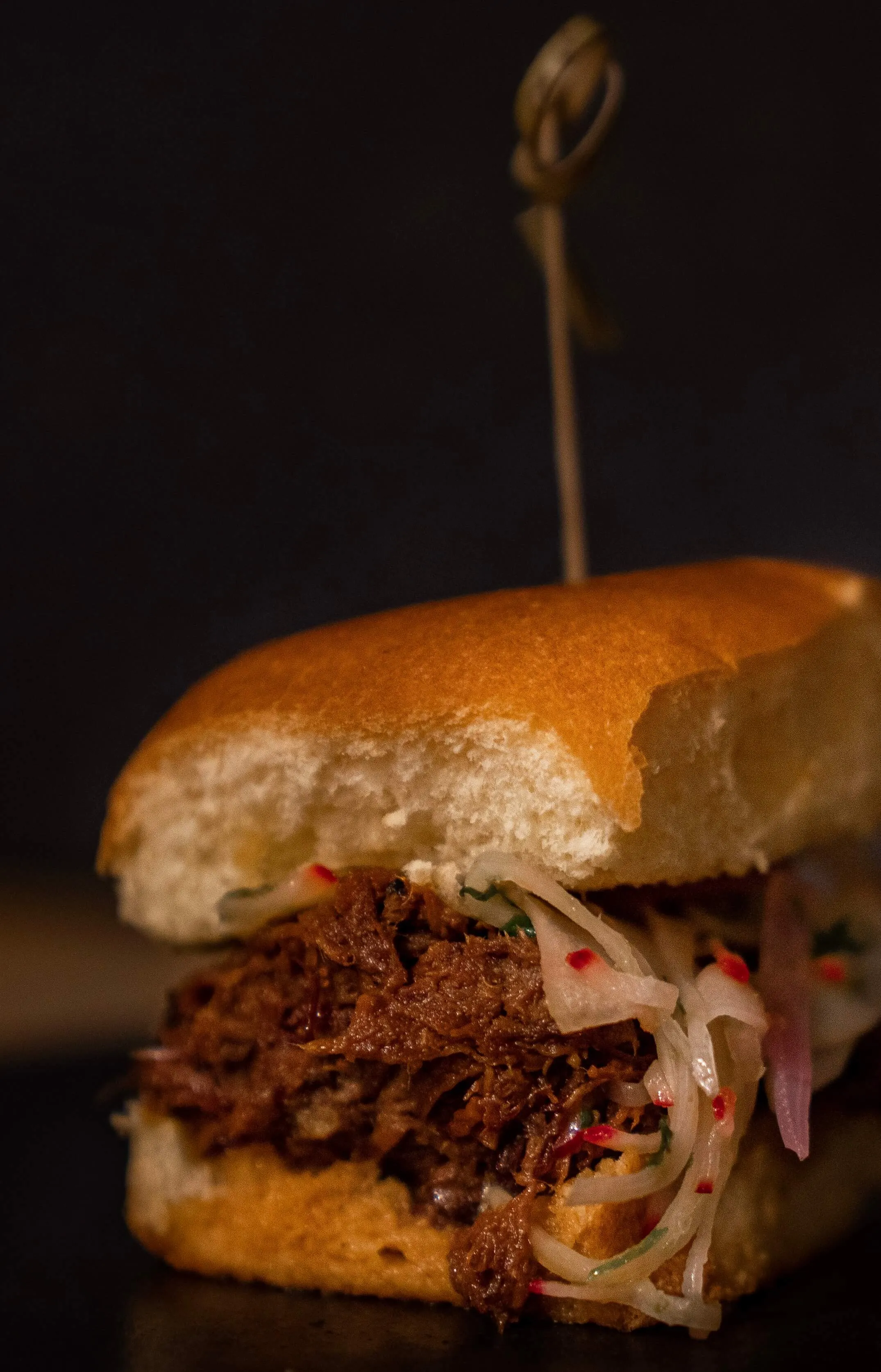 Pulled pork slider on a brioche bun topped with pickled slaw
