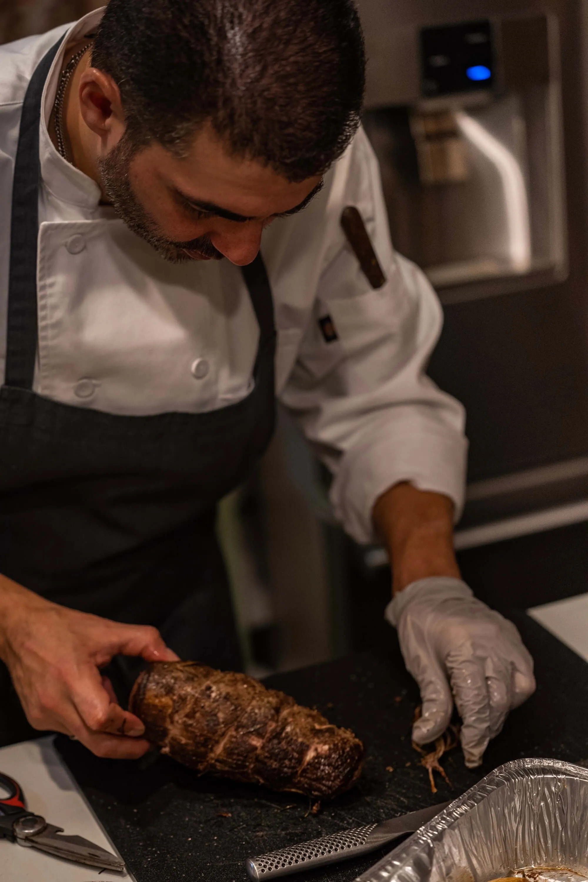 Chef in whites trussing a seasoned roast