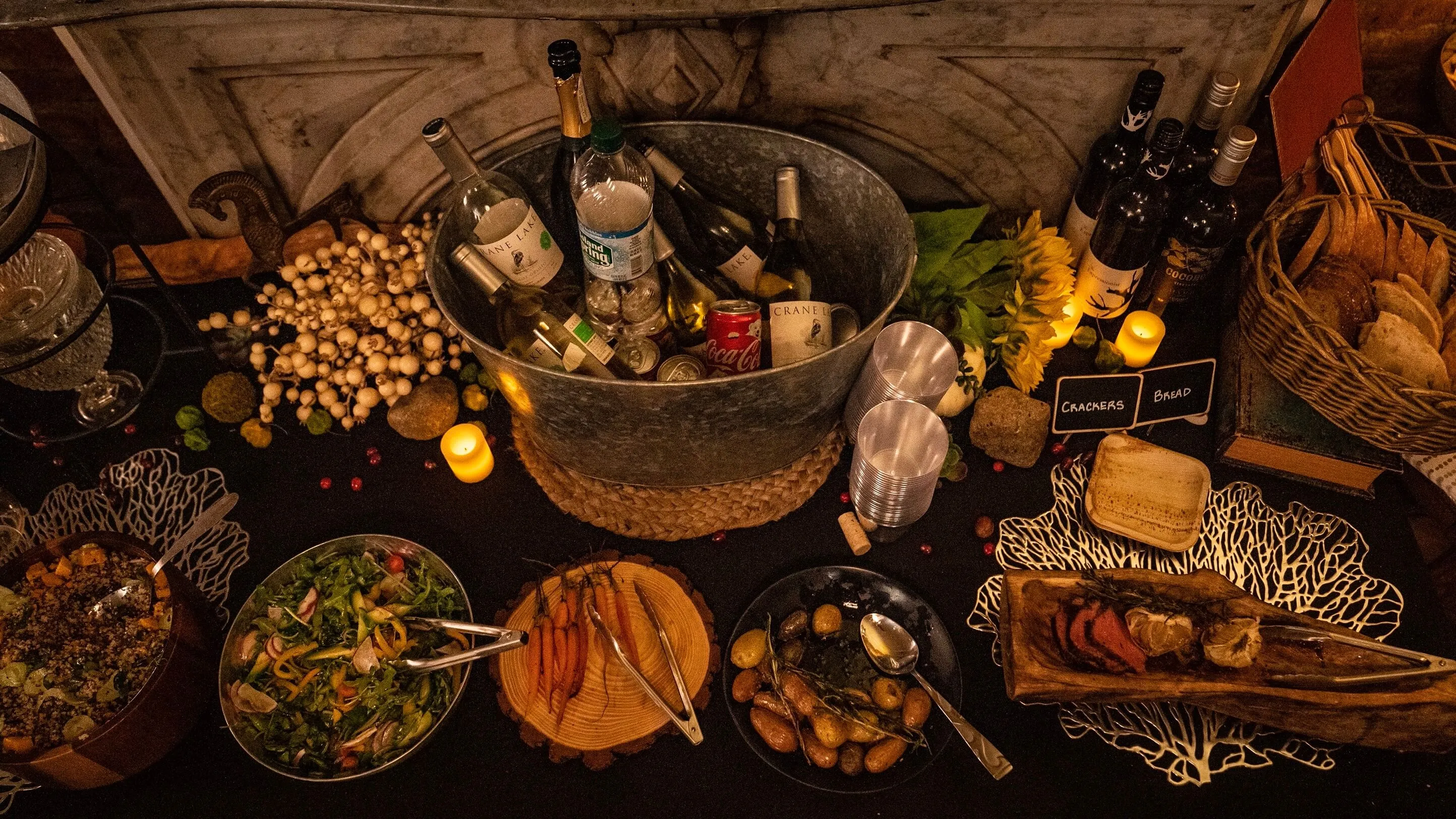 Overhead buffet spread with a wine tub, salad, and roasted vegetables