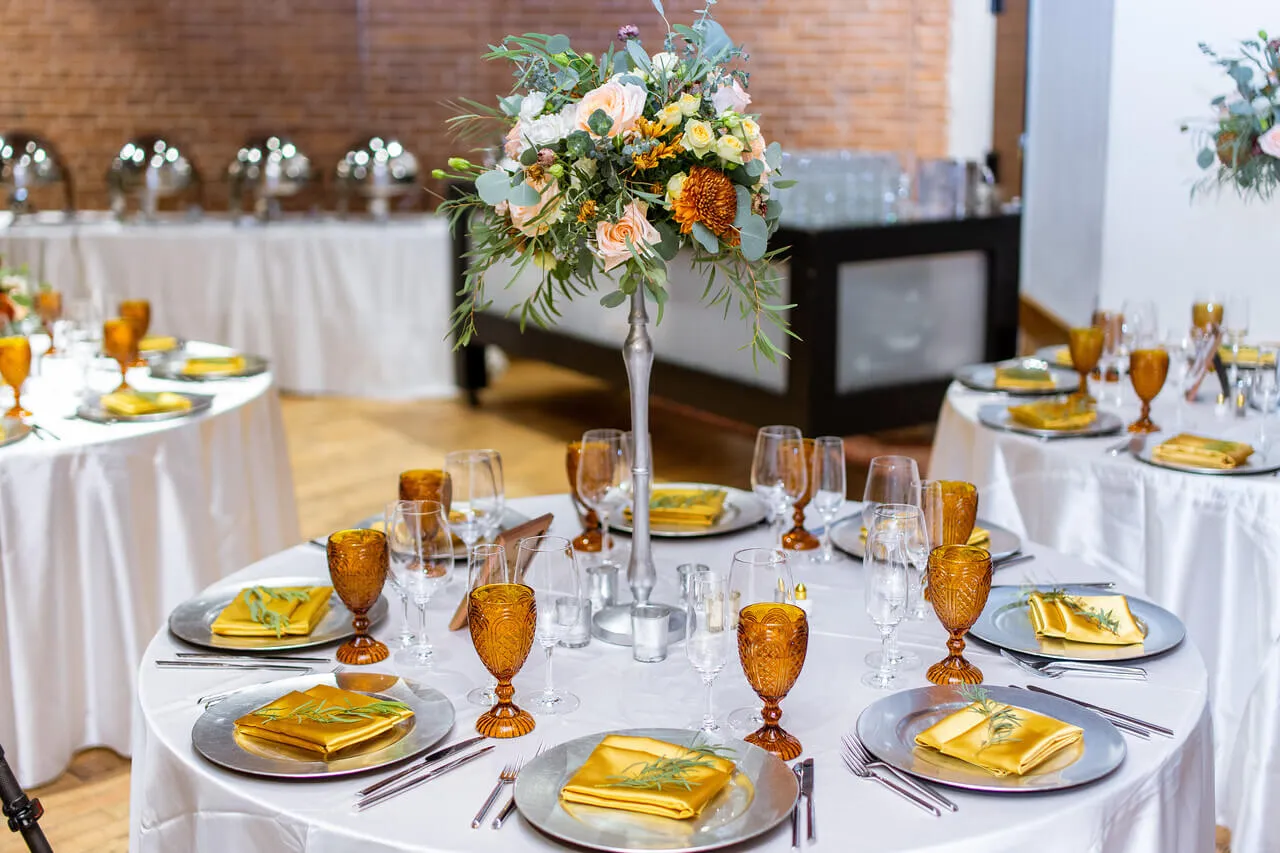 Round table setting with gold napkins and a floral centerpiece