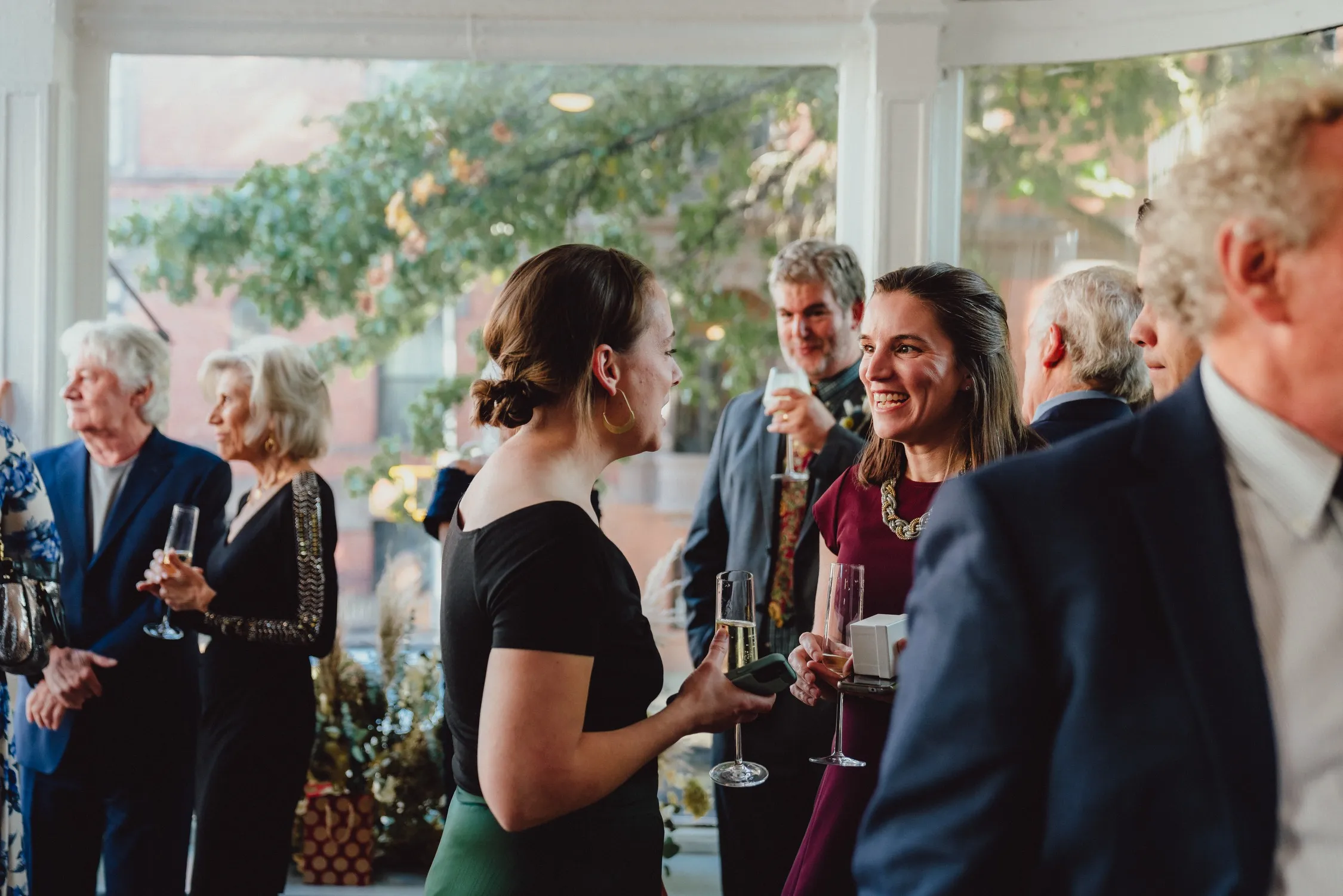Guests in cocktail attire chatting and holding champagne at a reception