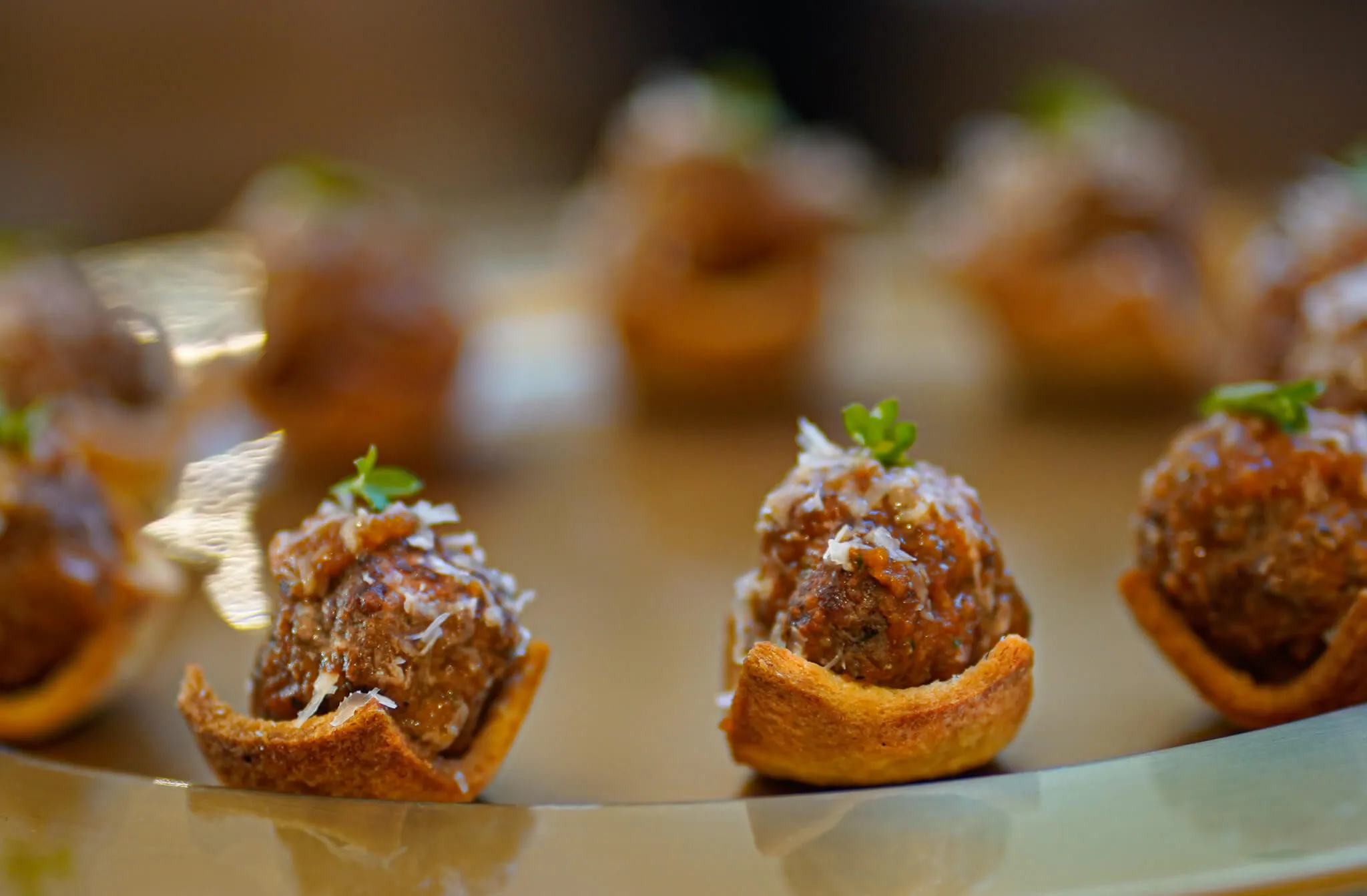 Mini meatballs in toasted bread cups topped with grated parmesan
