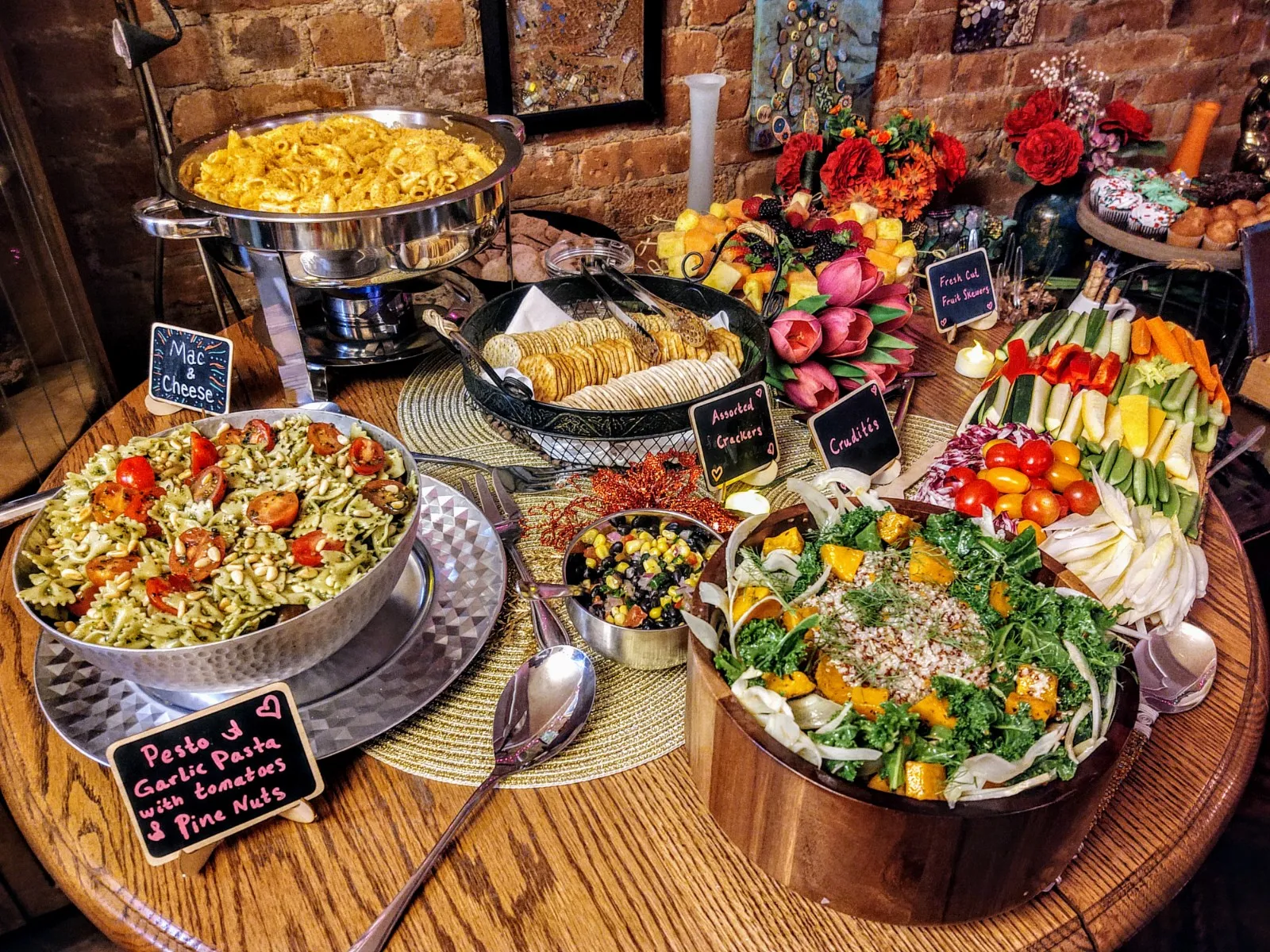 Buffet with mac and cheese, pesto pasta salad, crudités, and fruit skewers