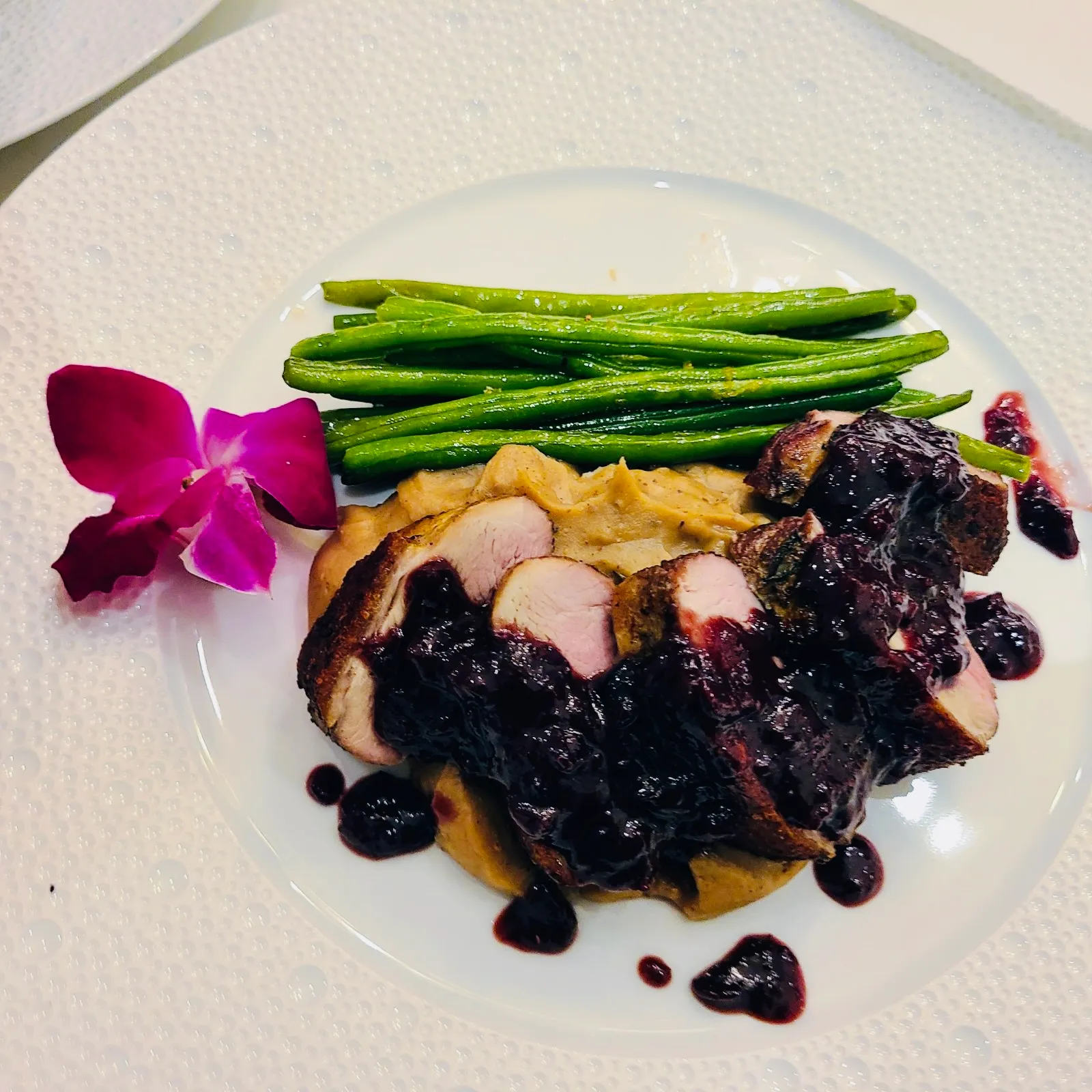 Sliced pork tenderloin with blueberry sauce, mashed potatoes, and green beans