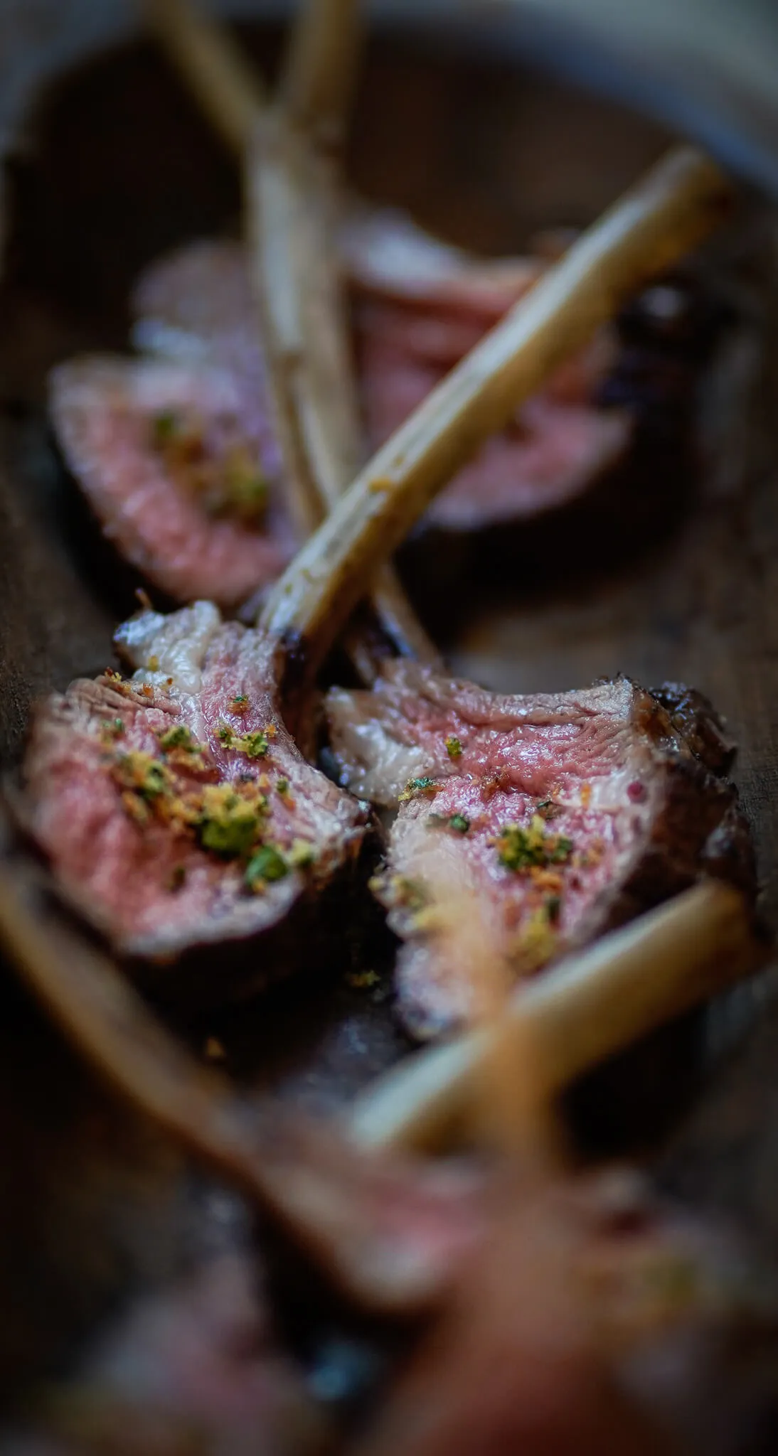 Herb-crusted rack of lamb chops cooked medium-rare on a wooden board