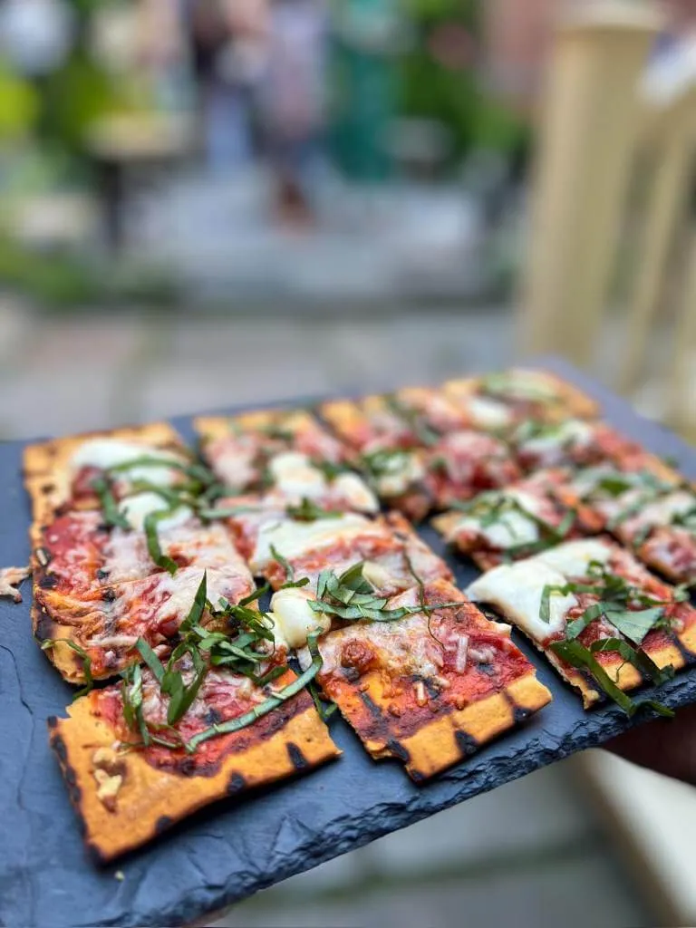 Grilled flatbread with mozzarella and fresh basil on a slate board