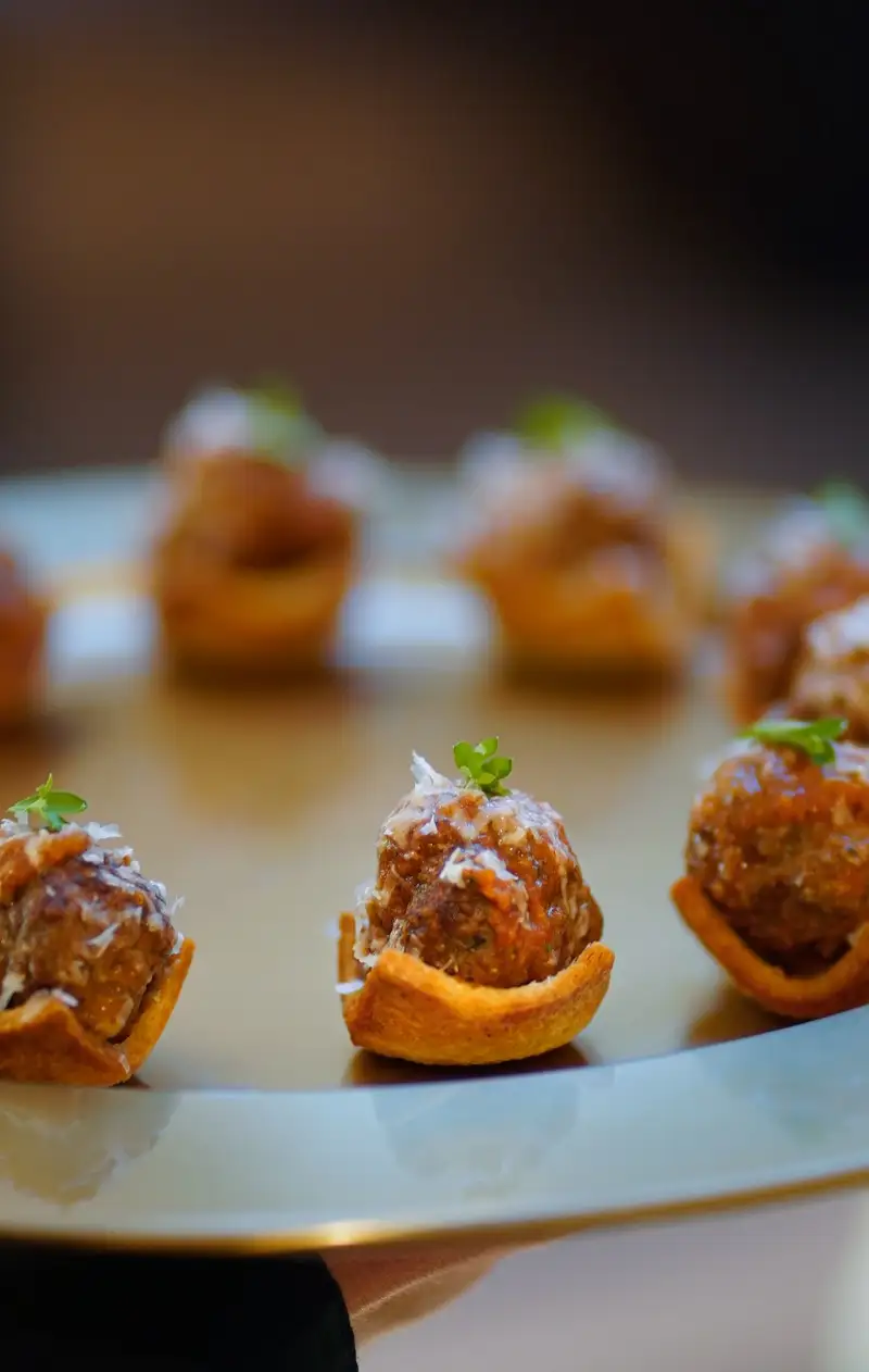 Meatball crostini cups garnished with parmesan and herbs