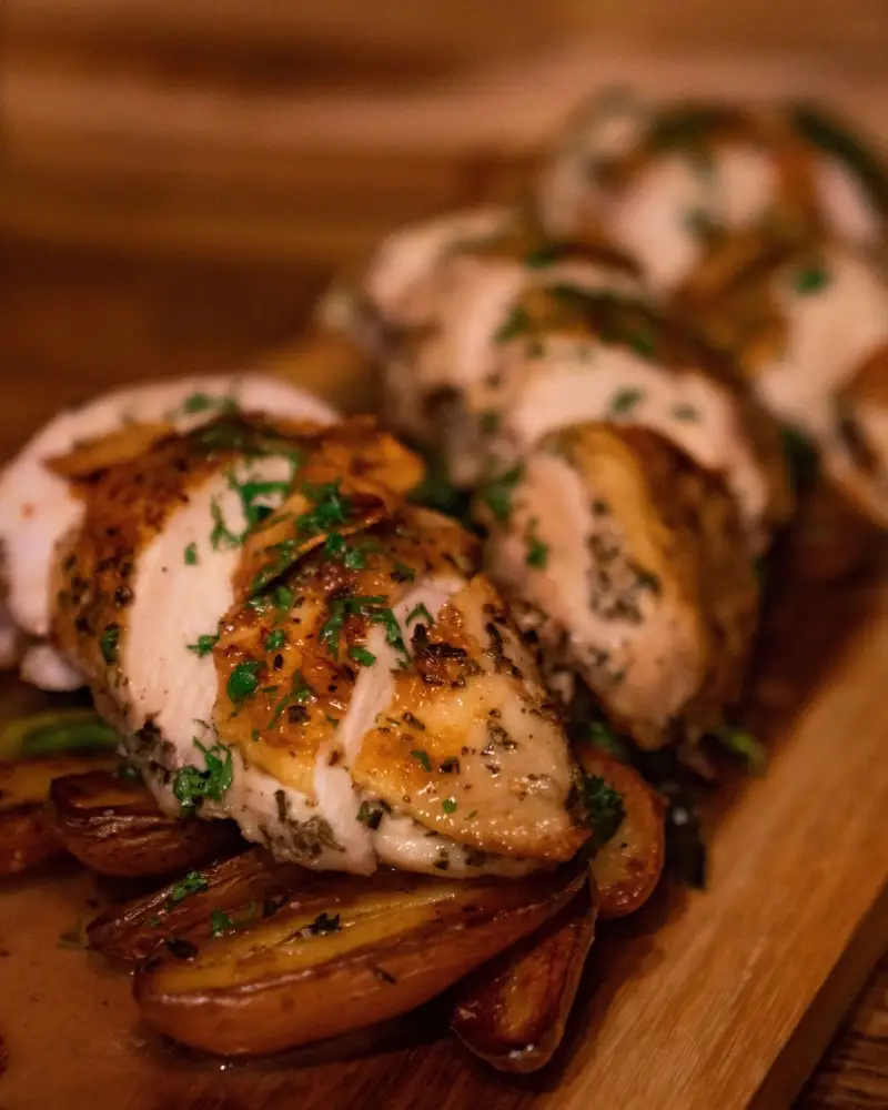 Sliced herb-roasted chicken breast over fingerling potatoes