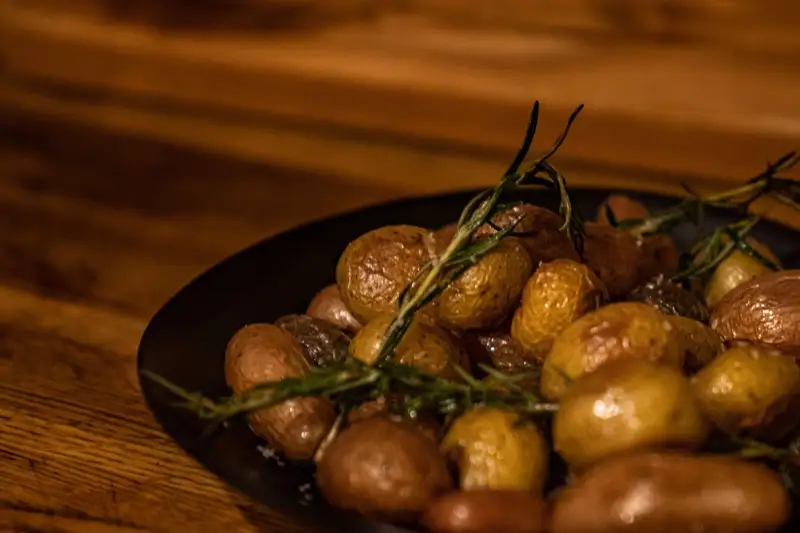 Roasted baby potatoes with rosemary on a black plate