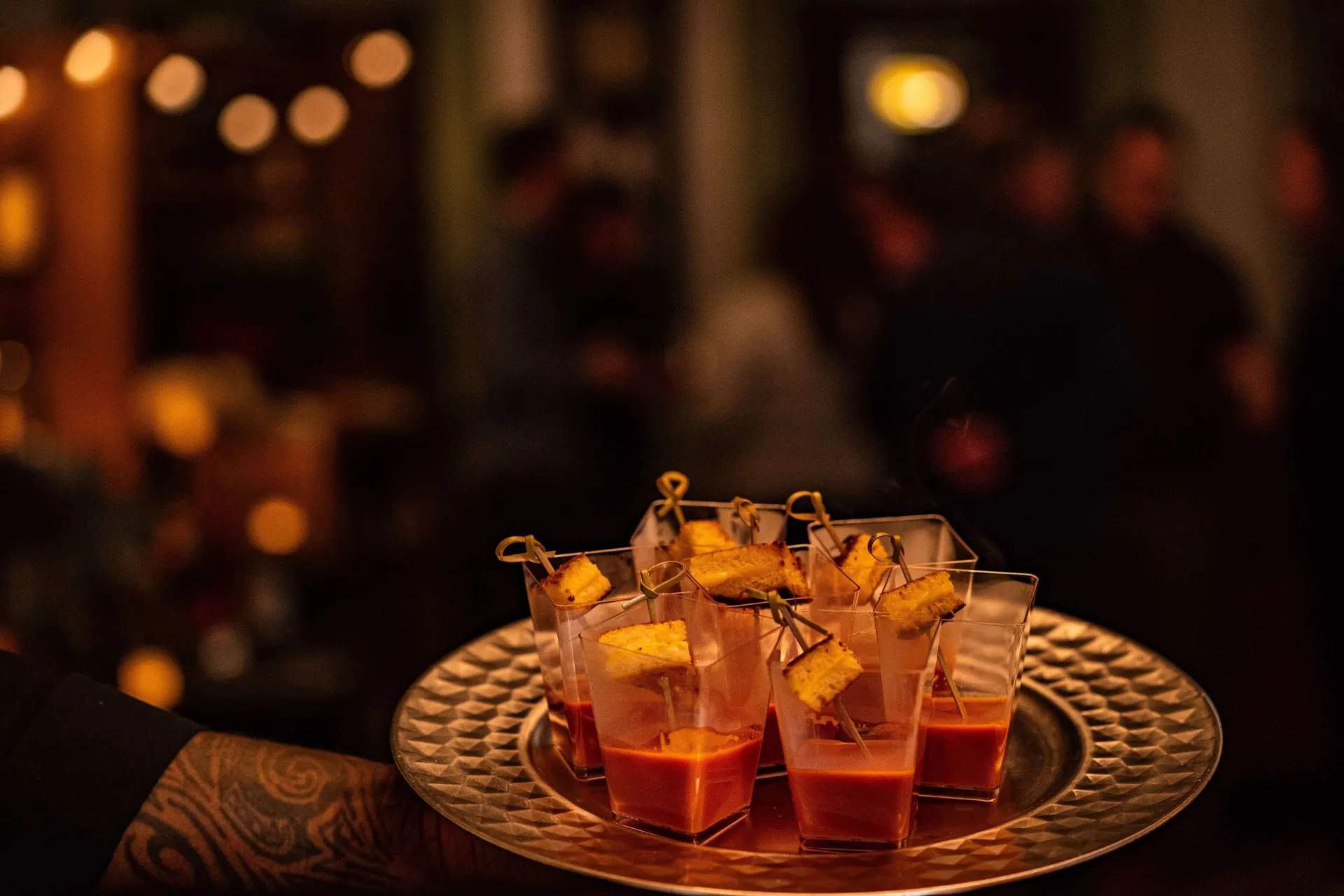 Tray of tomato soup shots with grilled cheese skewers at an event
