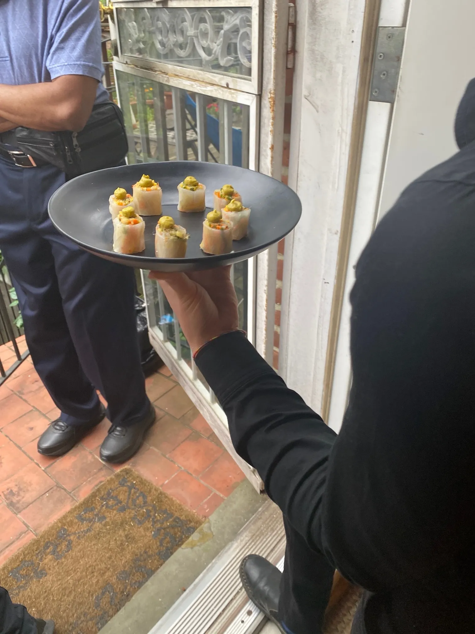Server holding a plate of summer rolls topped with avocado mousse