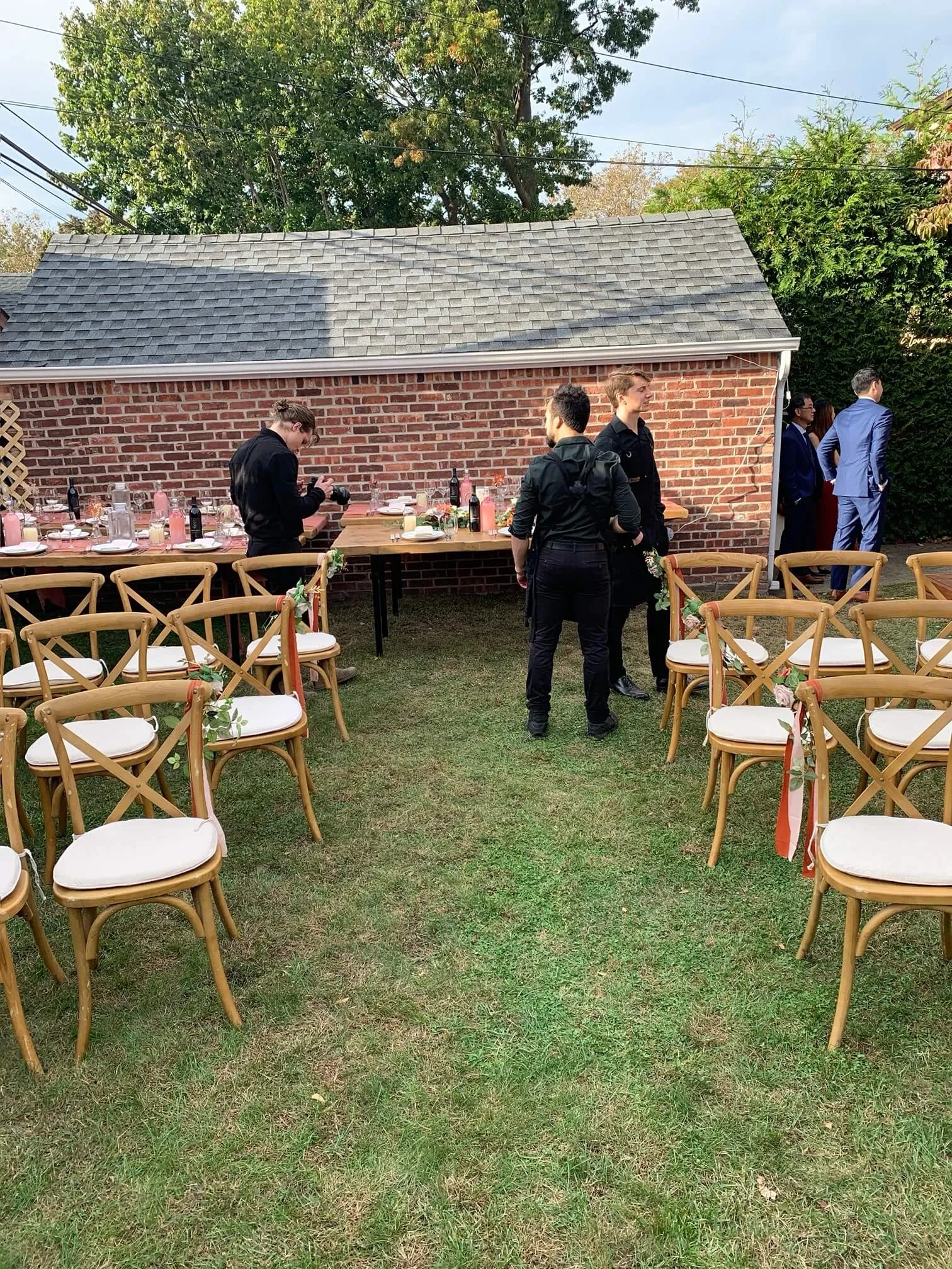Staff setting a long backyard dinner table before an outdoor ceremony