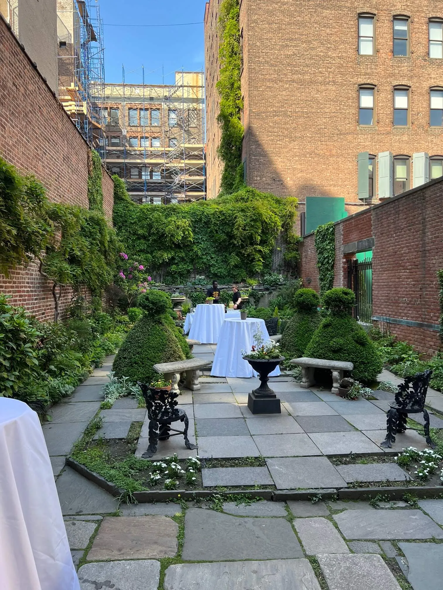 Cocktail-hour setup with linened tables in a brick courtyard garden
