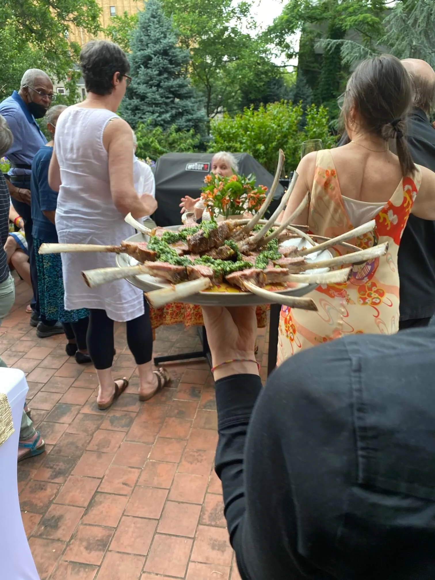 Server carrying a platter of frenched lamb chops with chimichurri