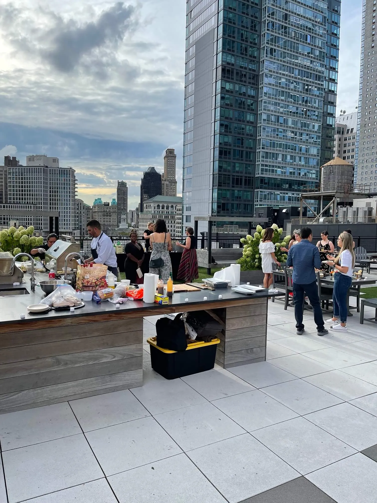Chef grilling at a rooftop station with the Manhattan skyline behind