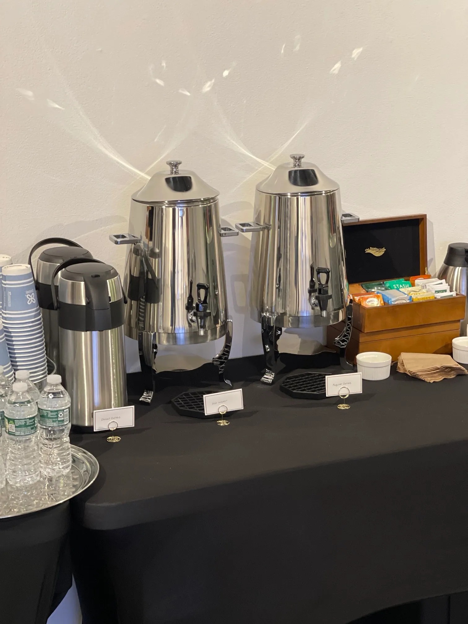 Two silver coffee urns and a tea selection on a beverage table
