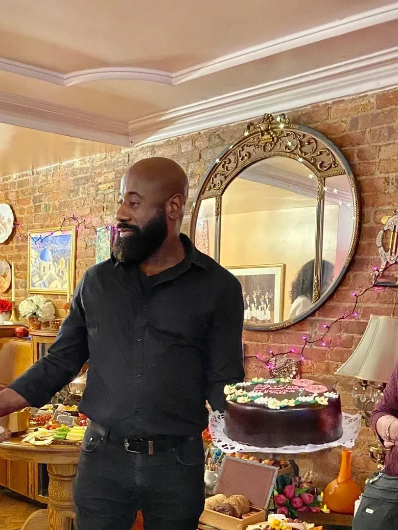 Server beside a chocolate celebration cake and grazing table