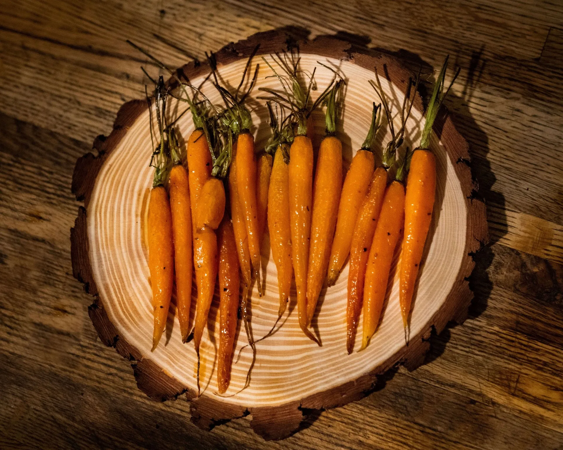Honey-glazed baby carrots on a rustic wood slice